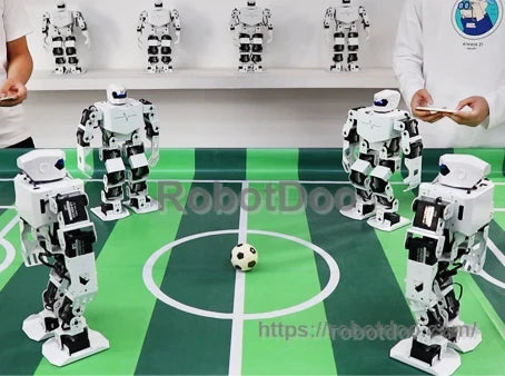 Multiple H5S humanoid robots gathered around a miniature soccer field