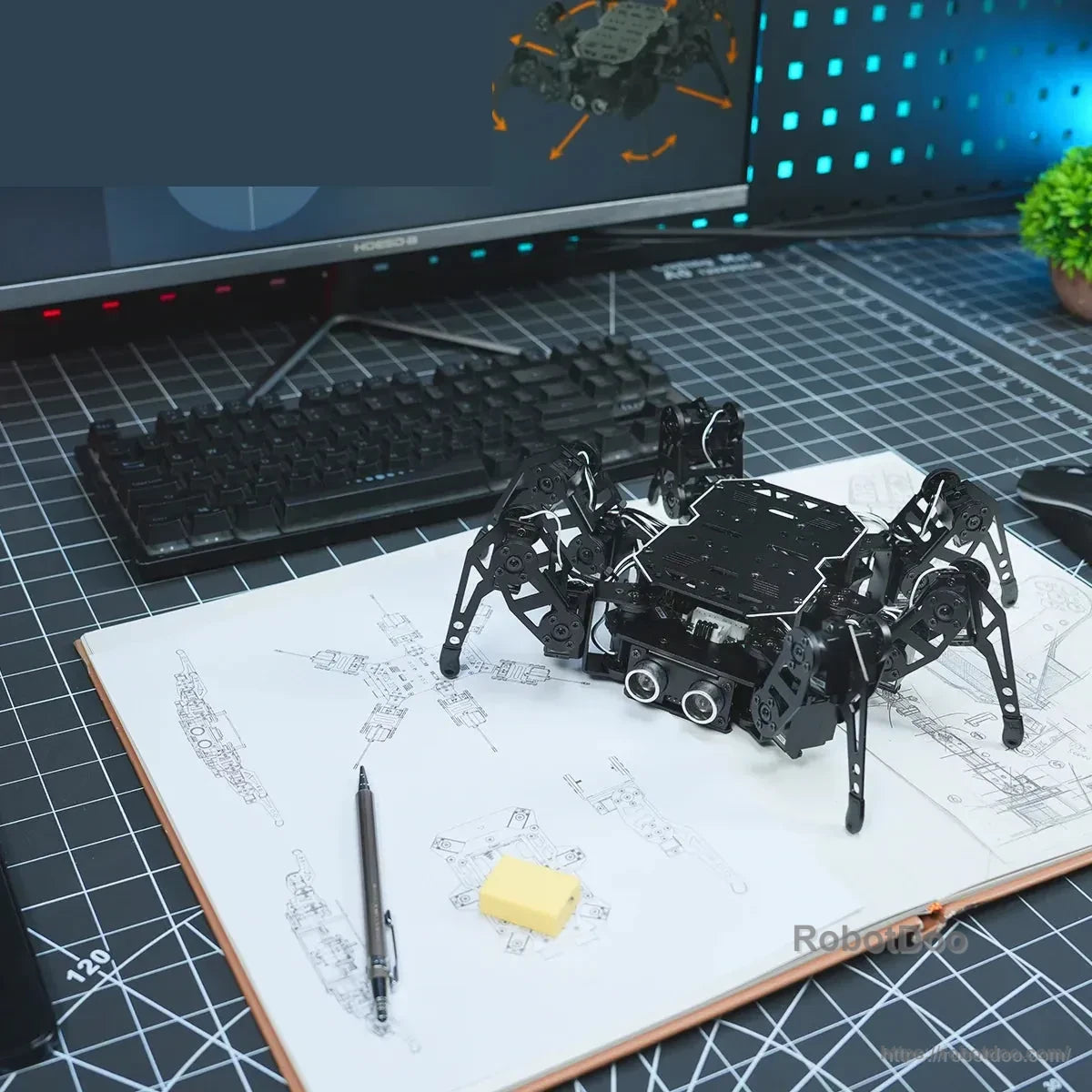 Hexapod robot on an instruction manual beside a computer workstation